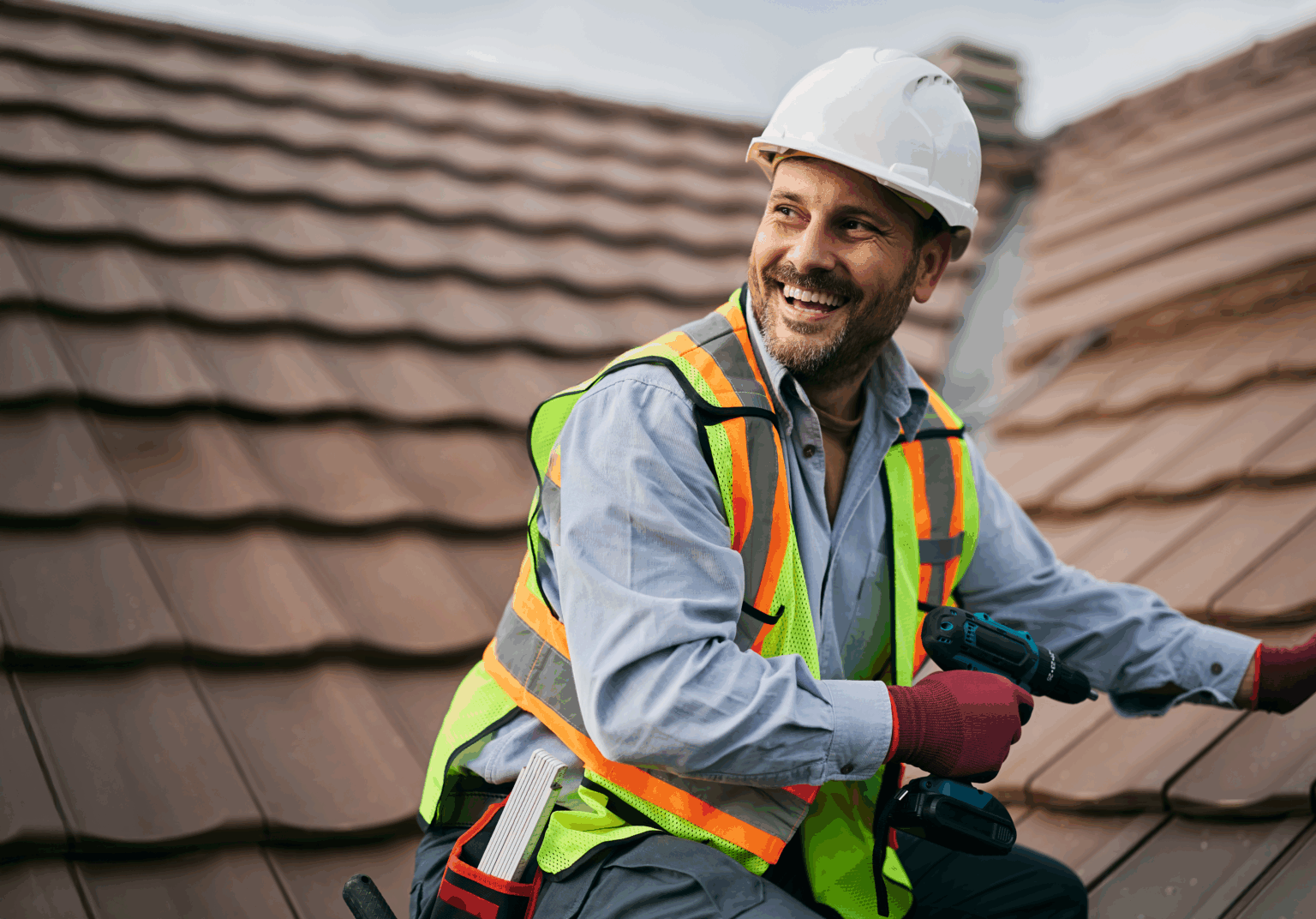 A roofer smiling while working on a roof